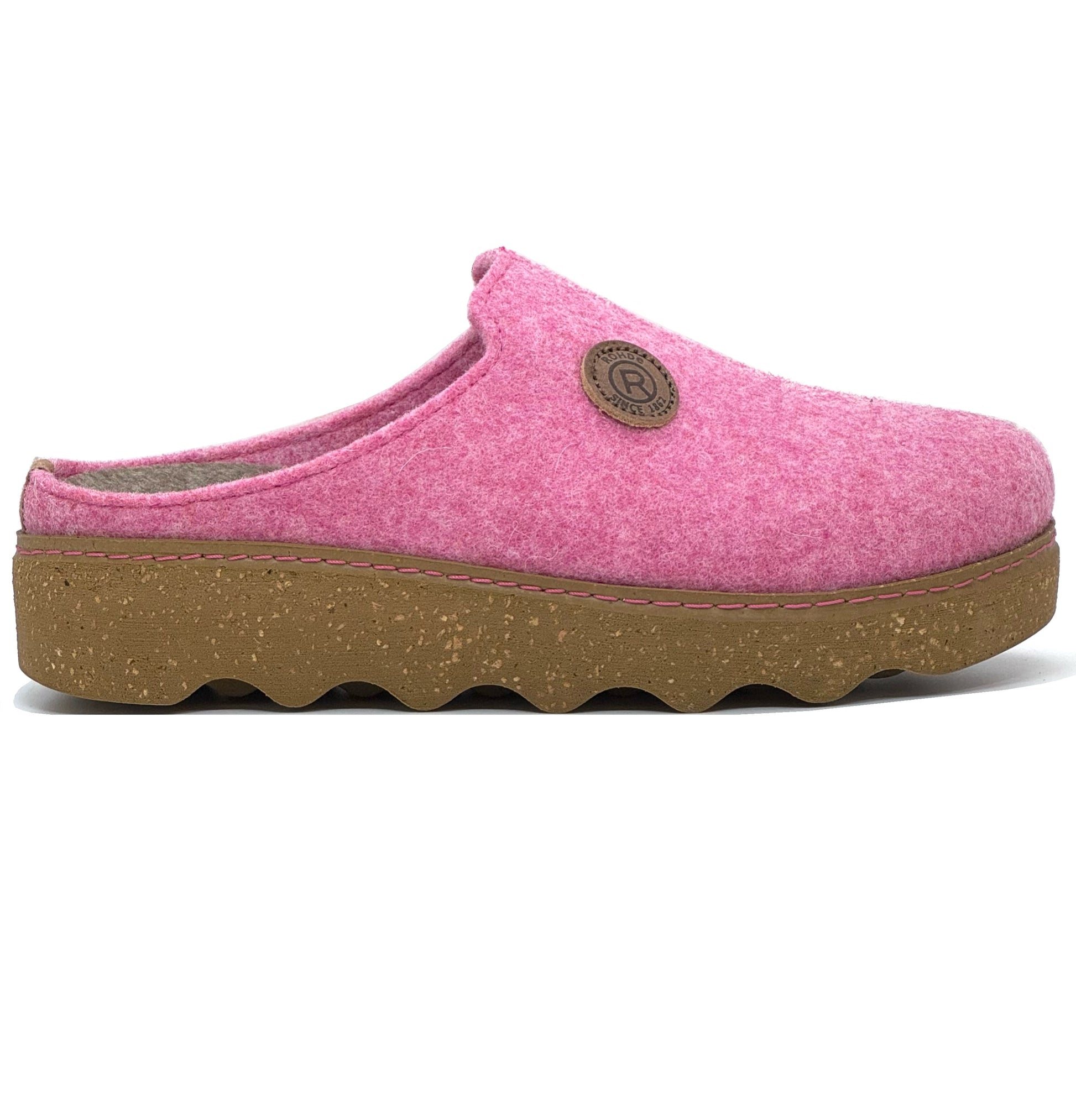 A pink woolen slipper with a chunky sole, featuring a label with a circular design on the top.
